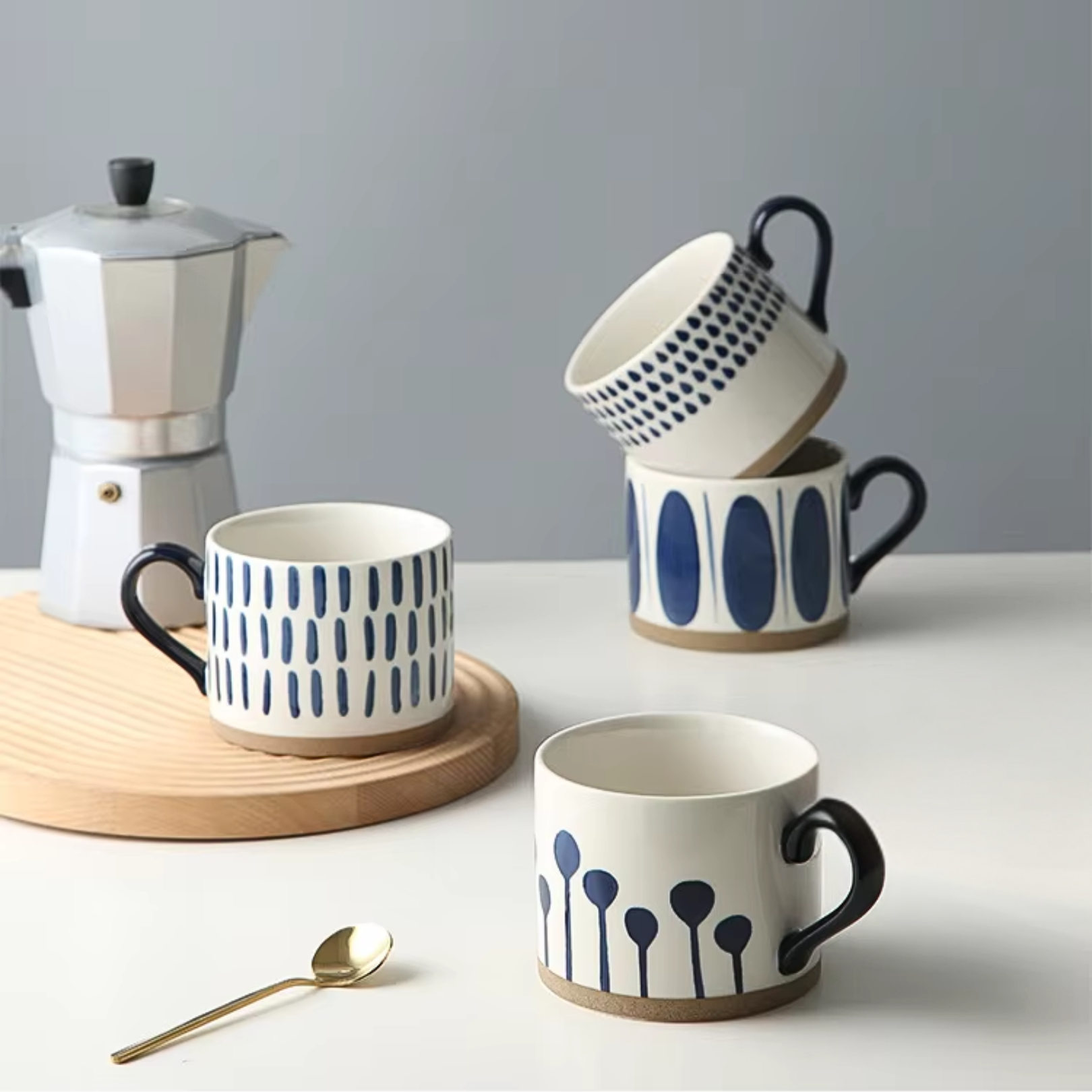 Several ceramic artisan mugs with different blue and white designs stacked or grouped, styled in a home setting