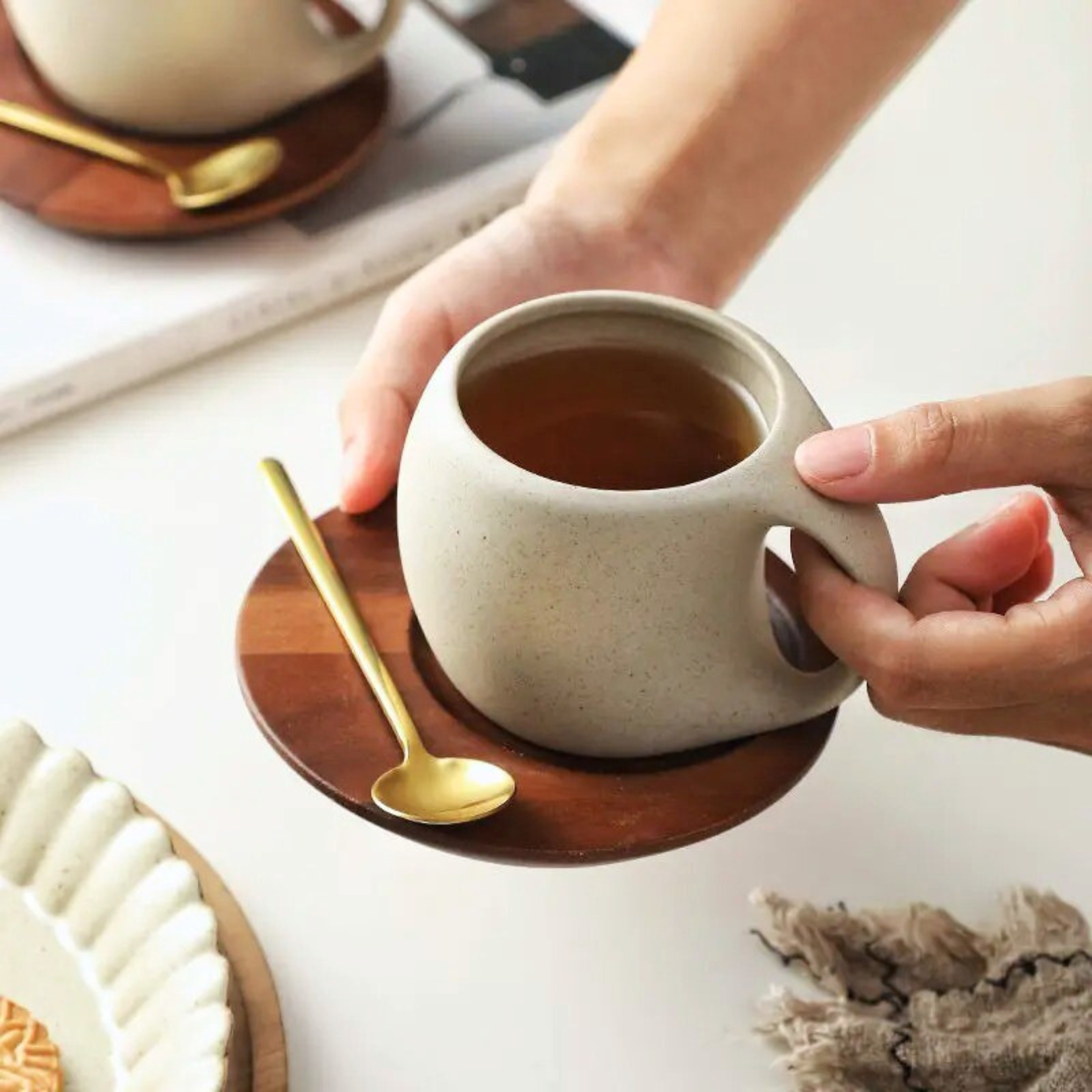 Ceramic cups on wooden bases with spoons styled in a lifestyle setup