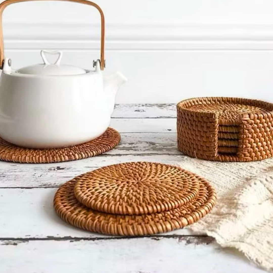 Rattan placemat with a kettle on top, styled on a rustic white wooden table, accompanied by matching rattan coasters for a cohesive natural look