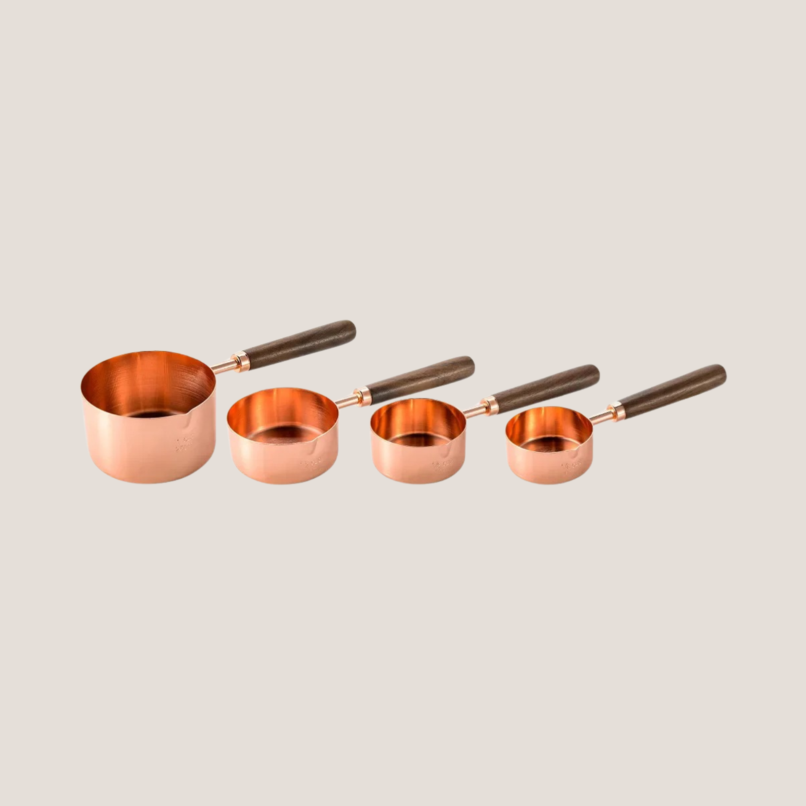 Set of rose measuring cups arranged in order from largest to smallest, neatly fanned out to show size variation