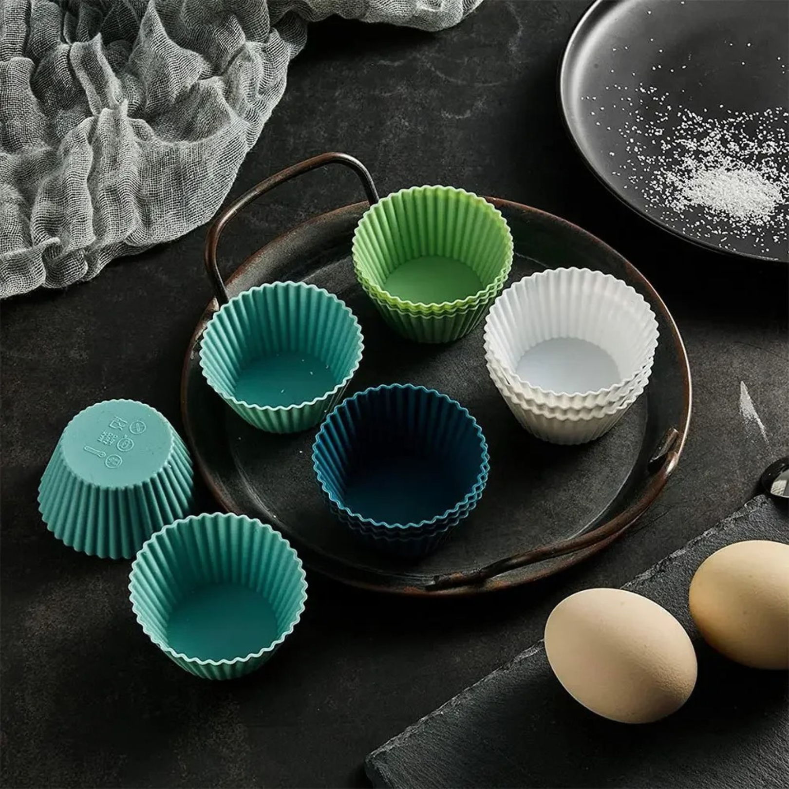 Silicone muffin cups displayed alongside baking ingredients in a stylish flat-lay kitchen setting