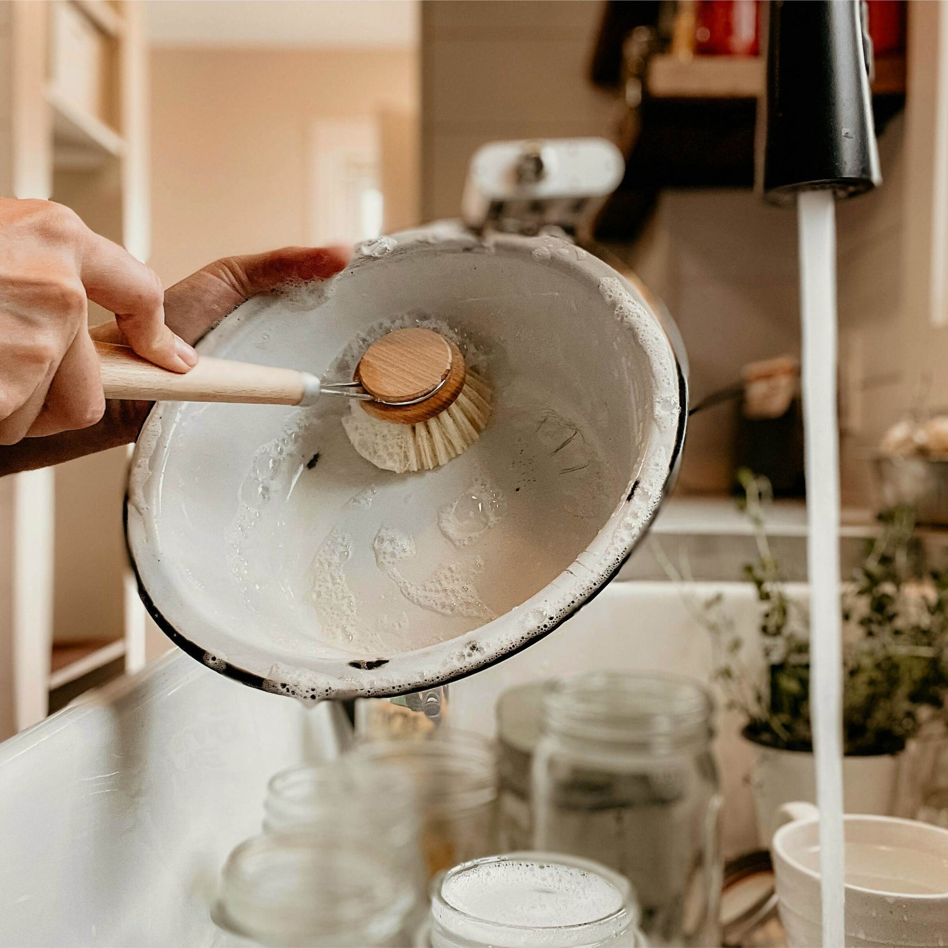 Sisal fiber brush scrubbing a pot or pan surface, showcasing clean lathered grooves
