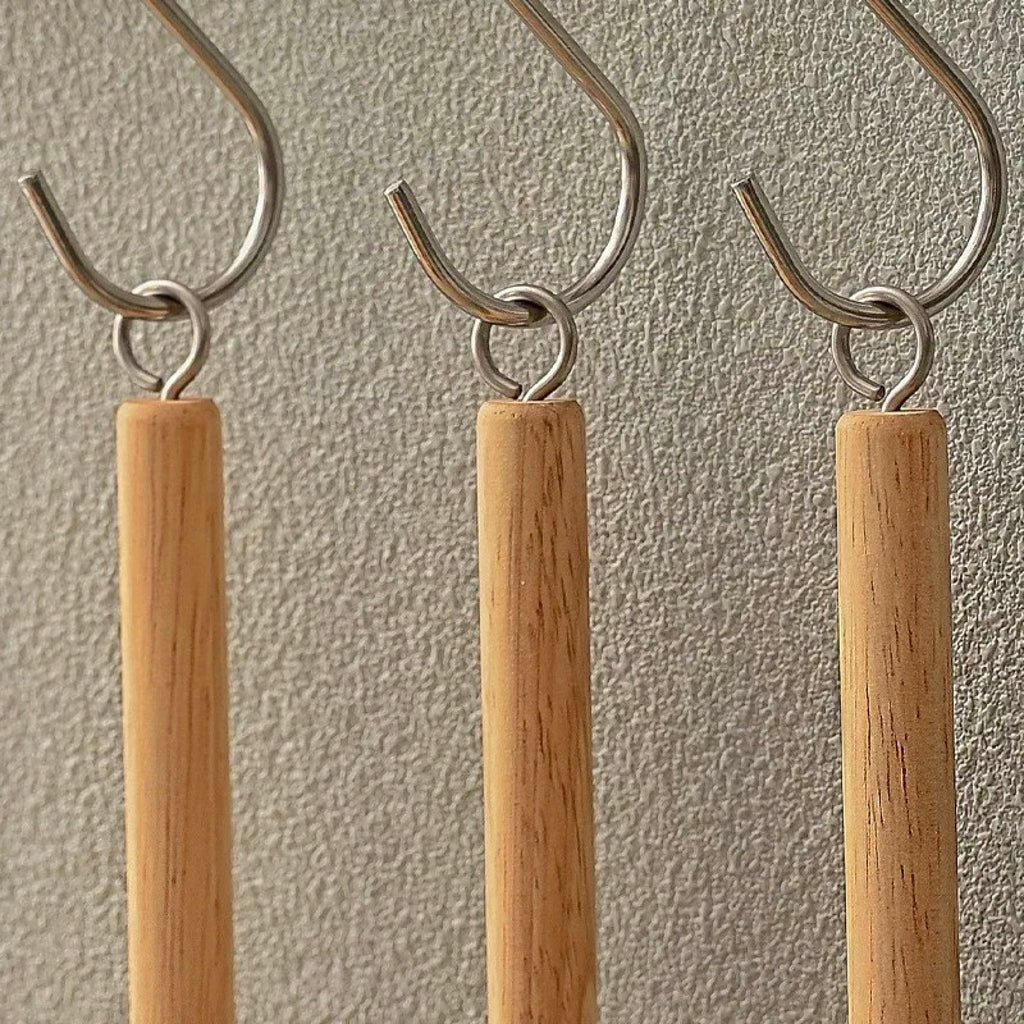 Three sisal dish brushes hanging by their metal hooks on a wall-mounted rack