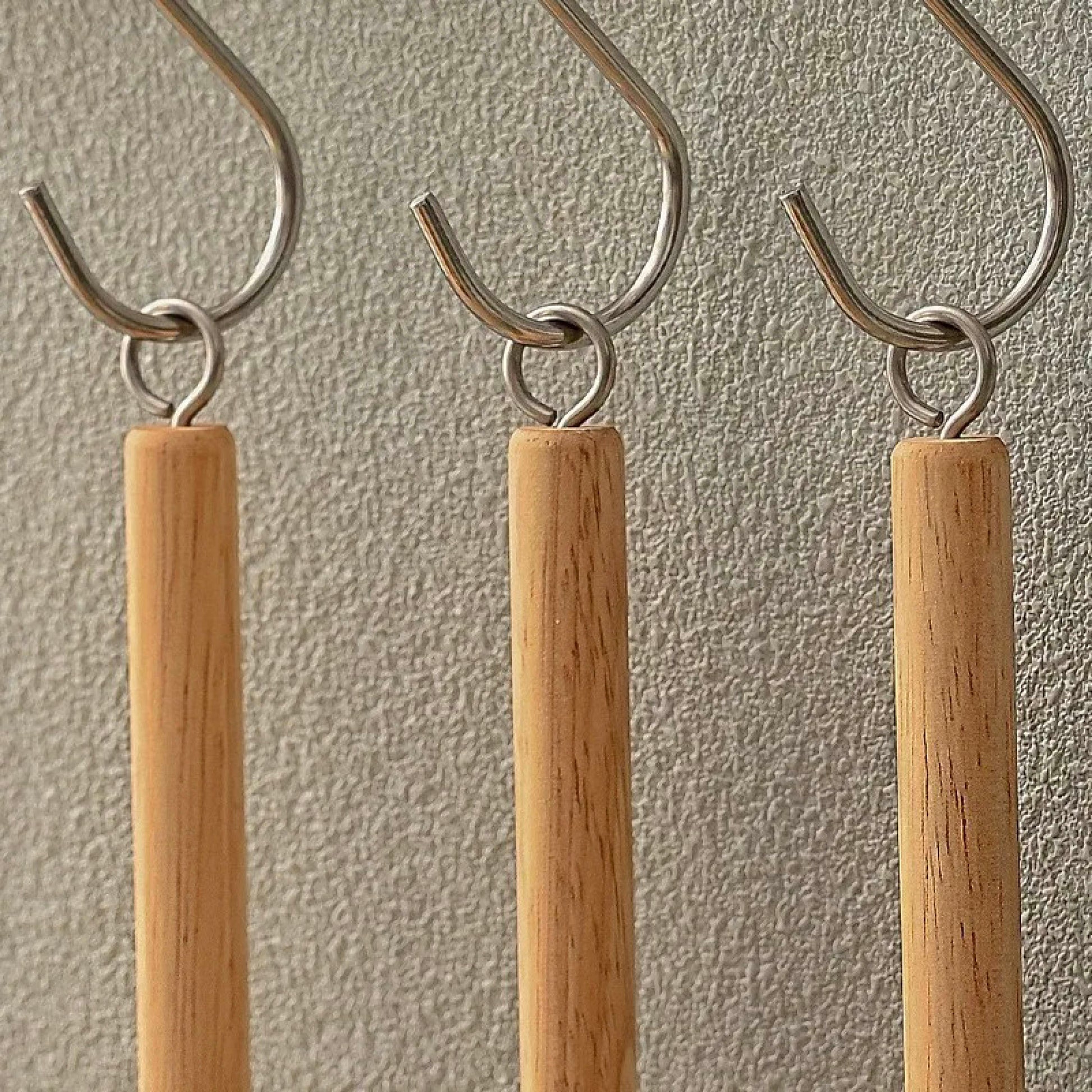 Three sisal dish brushes hanging by their metal hooks on a wall-mounted rack