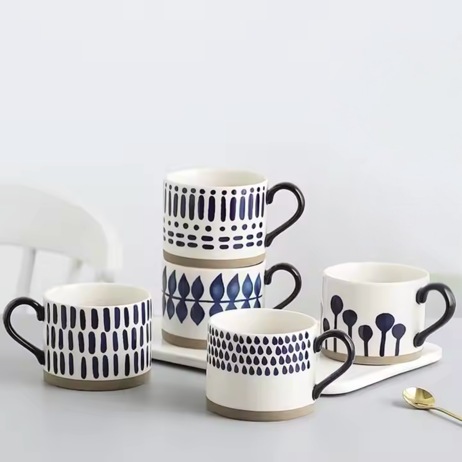 All four ceramic artisan mug designs stacked together in a cozy lifestyle setting