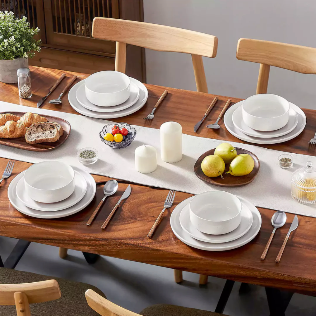 Ivory white stoneware dining set arranged on a dining table with cutlery, napkins, and glasses in a cozy dining setup