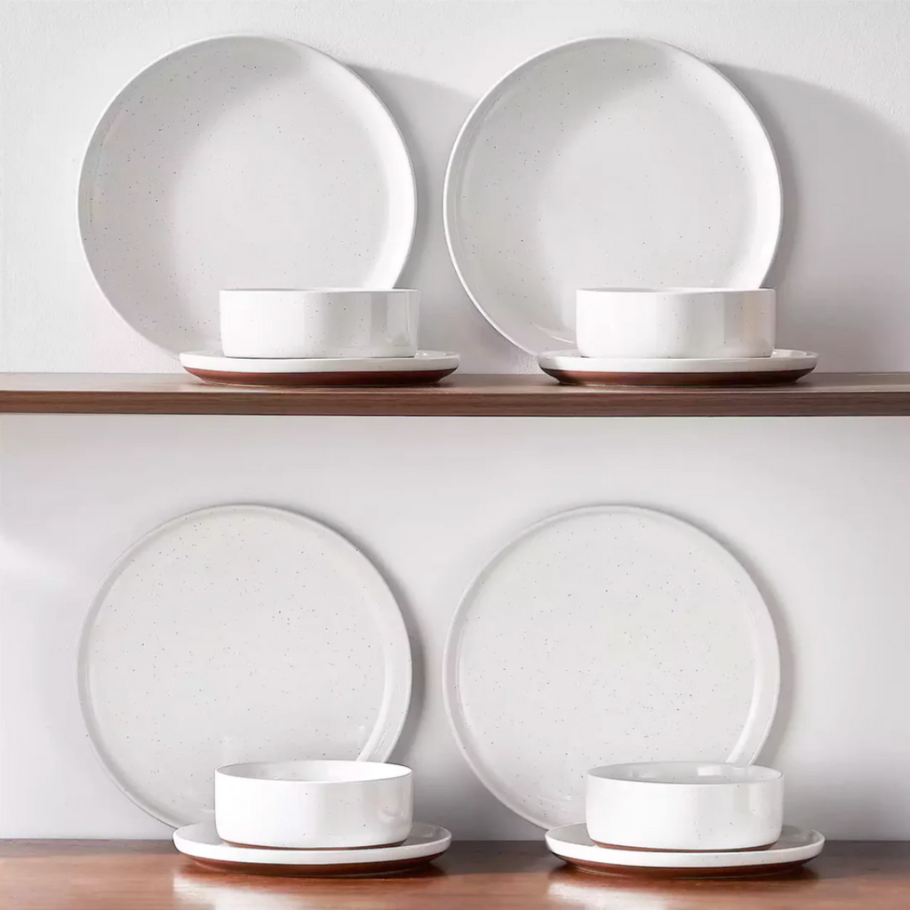 Ivory white stoneware dinnerware neatly arranged on a wooden shelf, showcasing its warm tones and rustic charm