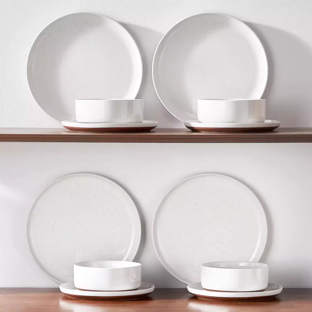 Ivory white stoneware dinnerware neatly arranged on a wooden shelf, showcasing its warm tones and rustic charm
