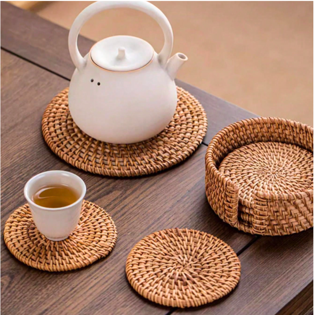 White kettle placed on a rattan placemat with a tea cup beside it on a rustic wooden table