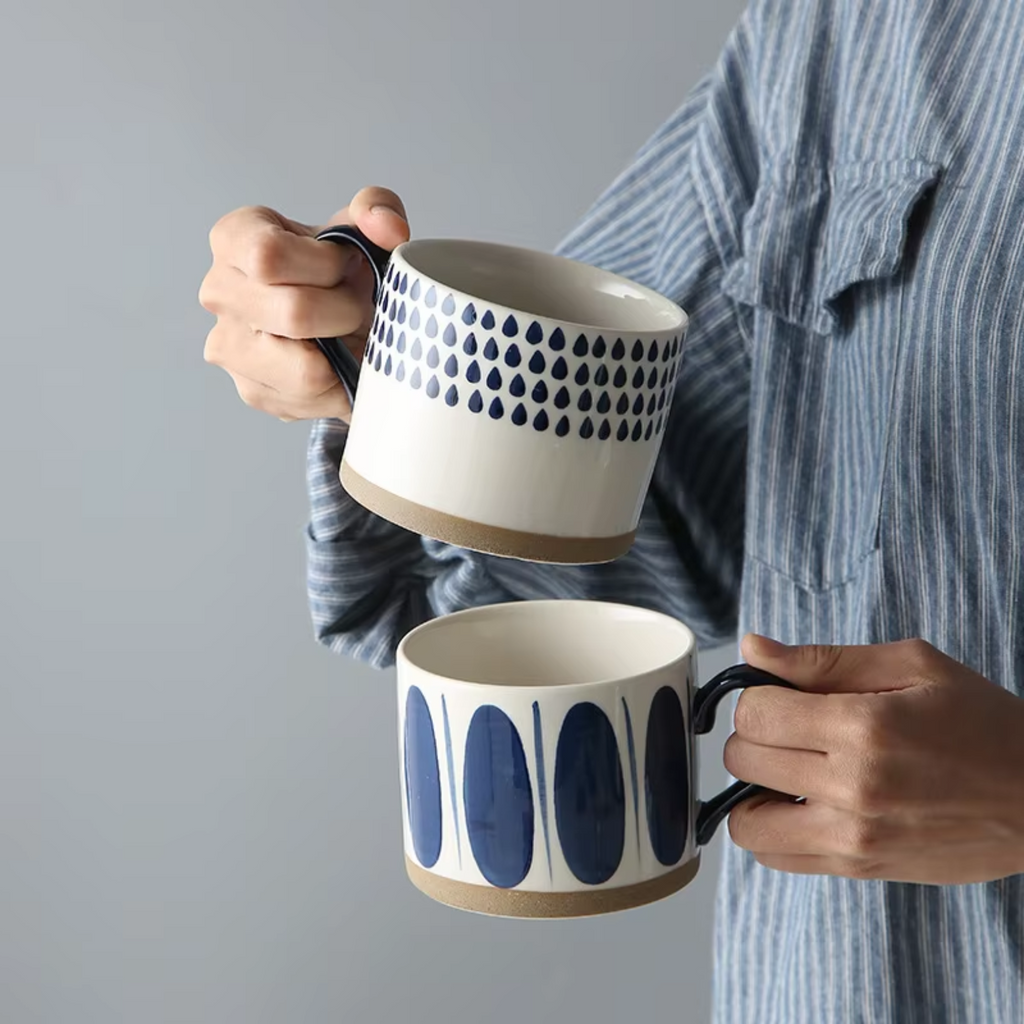 Woman holding two ceramic artisan mugs, one in each hand, showcasing their unique design and glaze