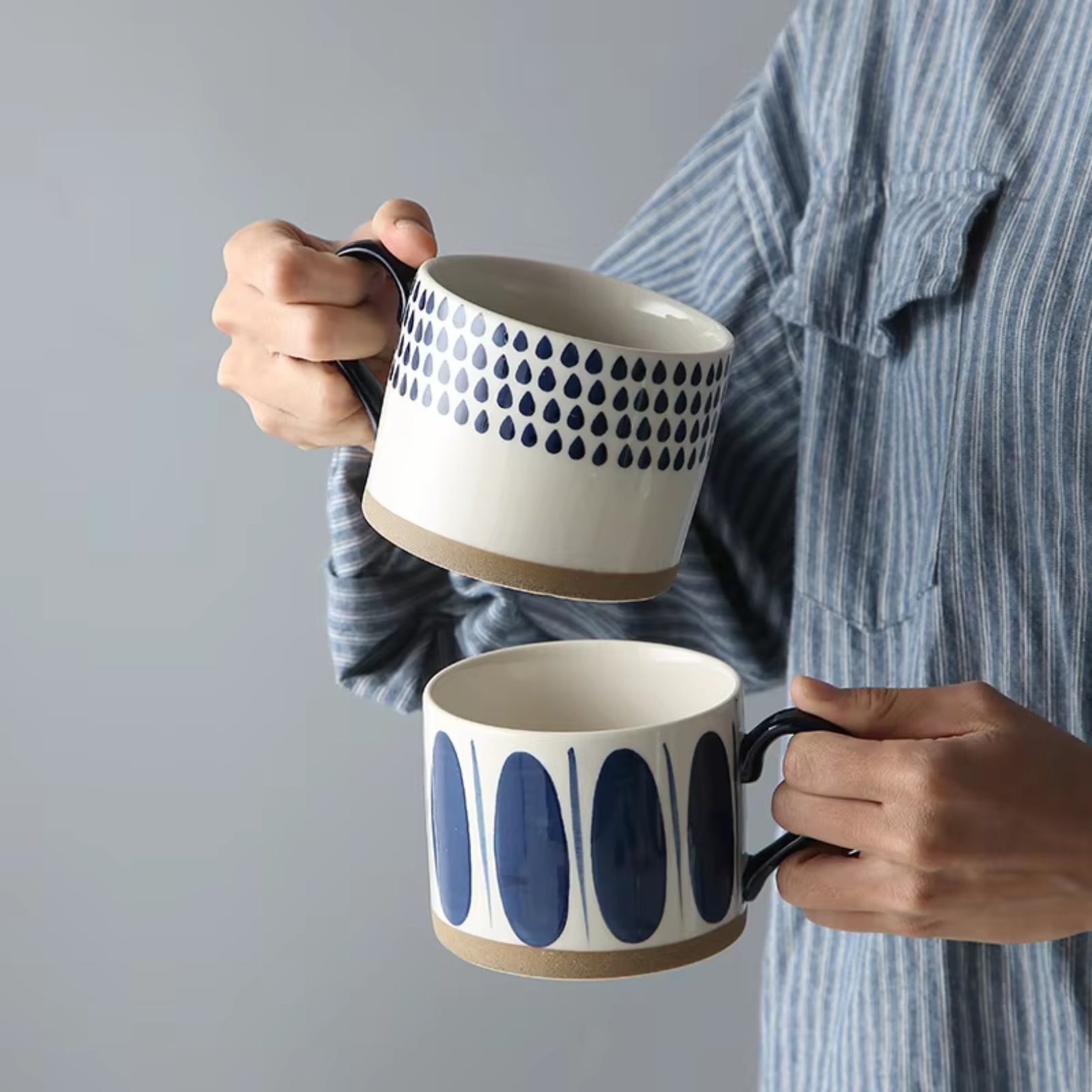 Woman holding two ceramic artisan mugs, one in each hand, showcasing their unique design and glaze