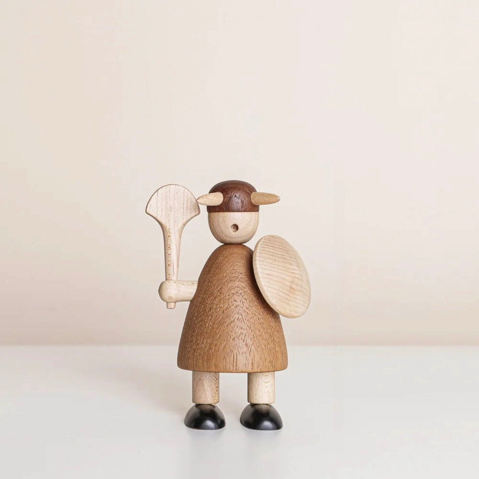 Hand-carved wooden Viking figurine holding a round shield and axe, wearing horned helmet