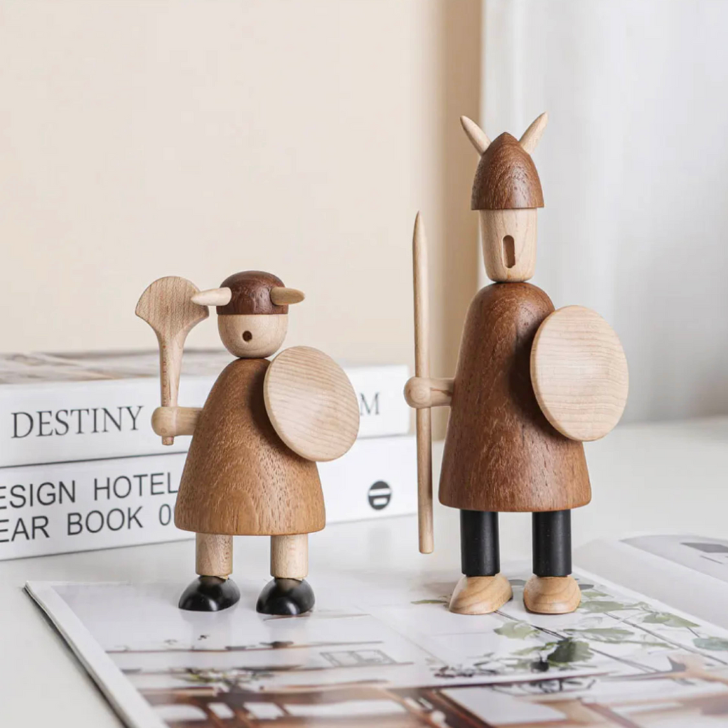 Side view of two wooden Viking figurines standing next to each other, showing shield and helmet profile