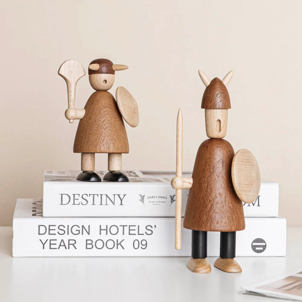 Two hand-carved wooden Viking figurines with decorated shields standing side by side