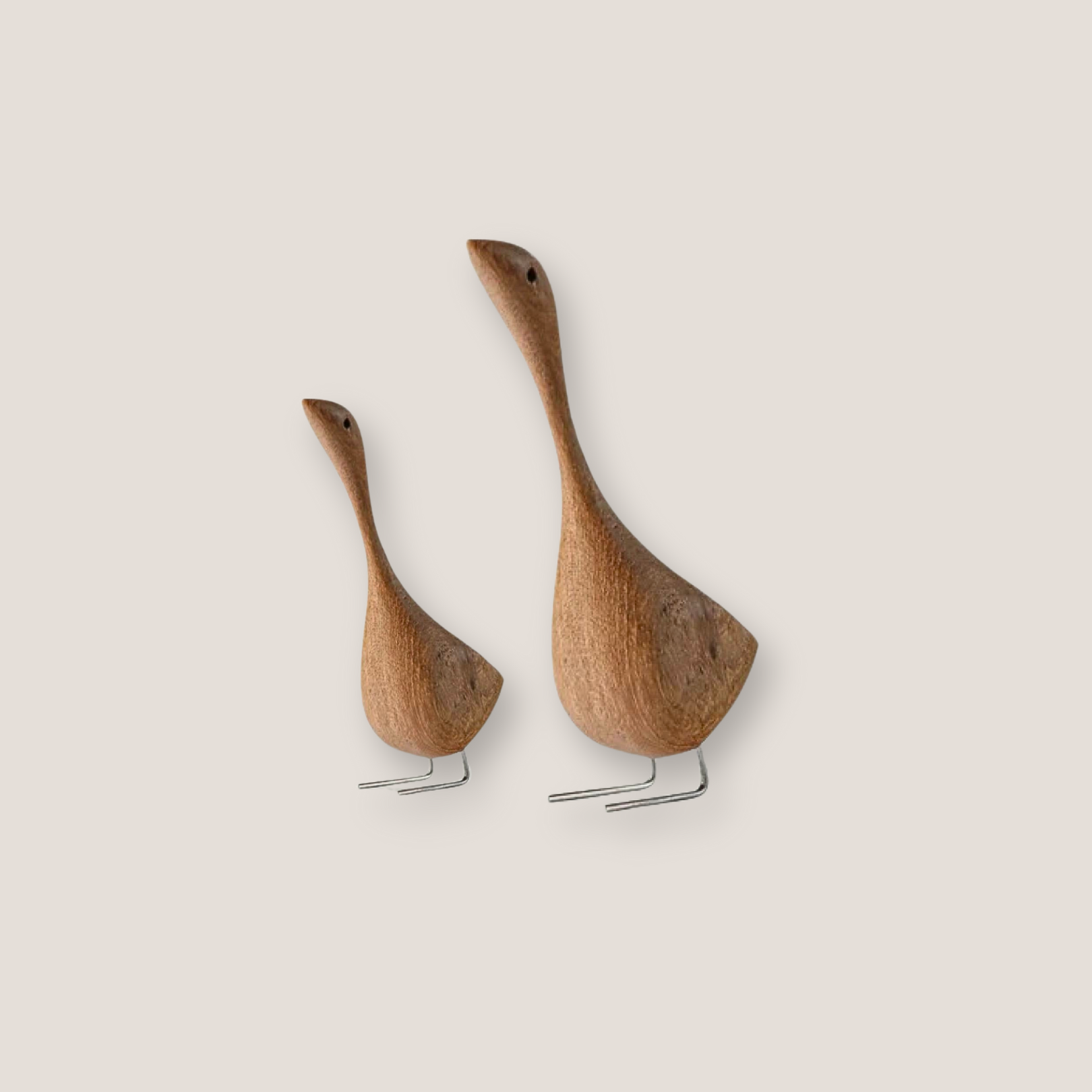 Two wooden goose figurines standing side by side on a white background